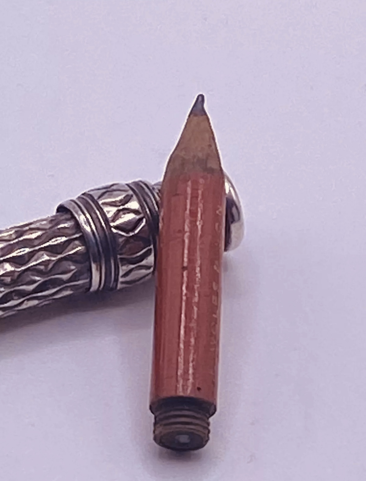 Detall del petit llapis de fusta separat del portallapis, amb la rosca de fixació visible